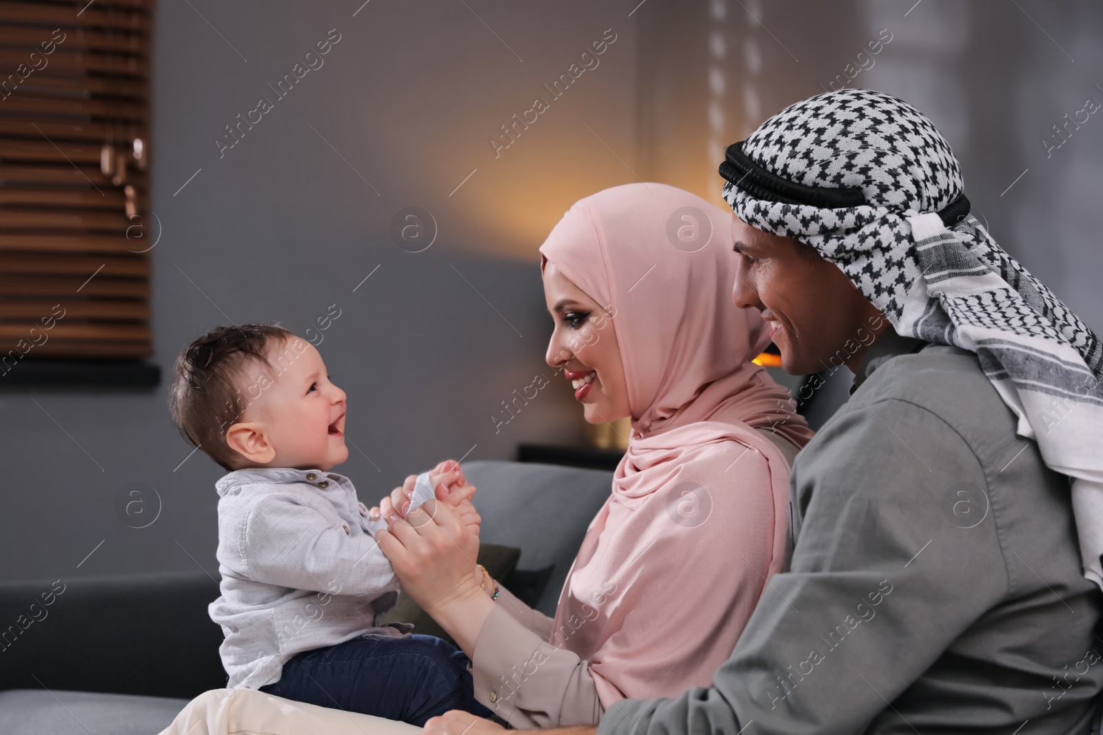 Photo of Happy Muslim family with little son in living room