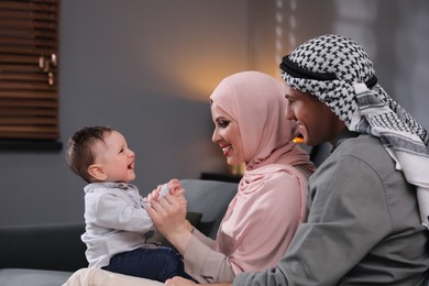 Happy Muslim family with little son in living room