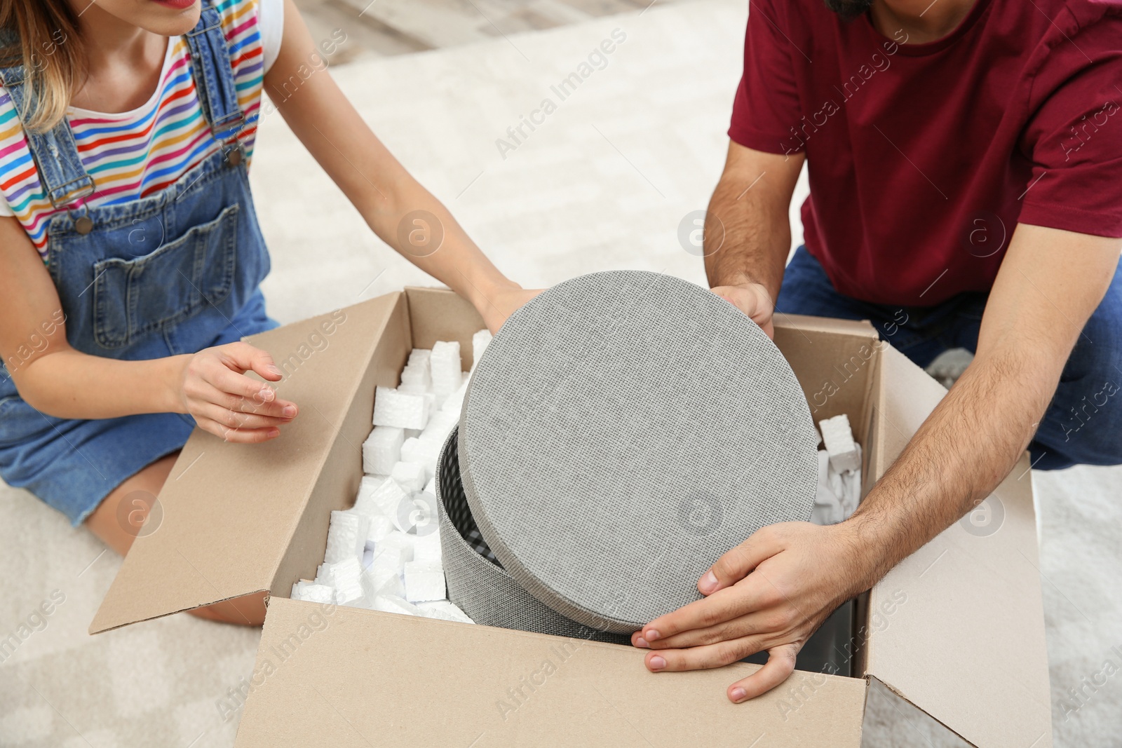 Photo of Young couple opening parcel on floor at home, closeup