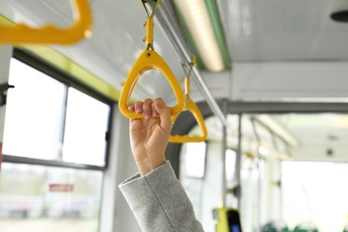 Photo of Woman holding handgrip handle in public transport, closeup
