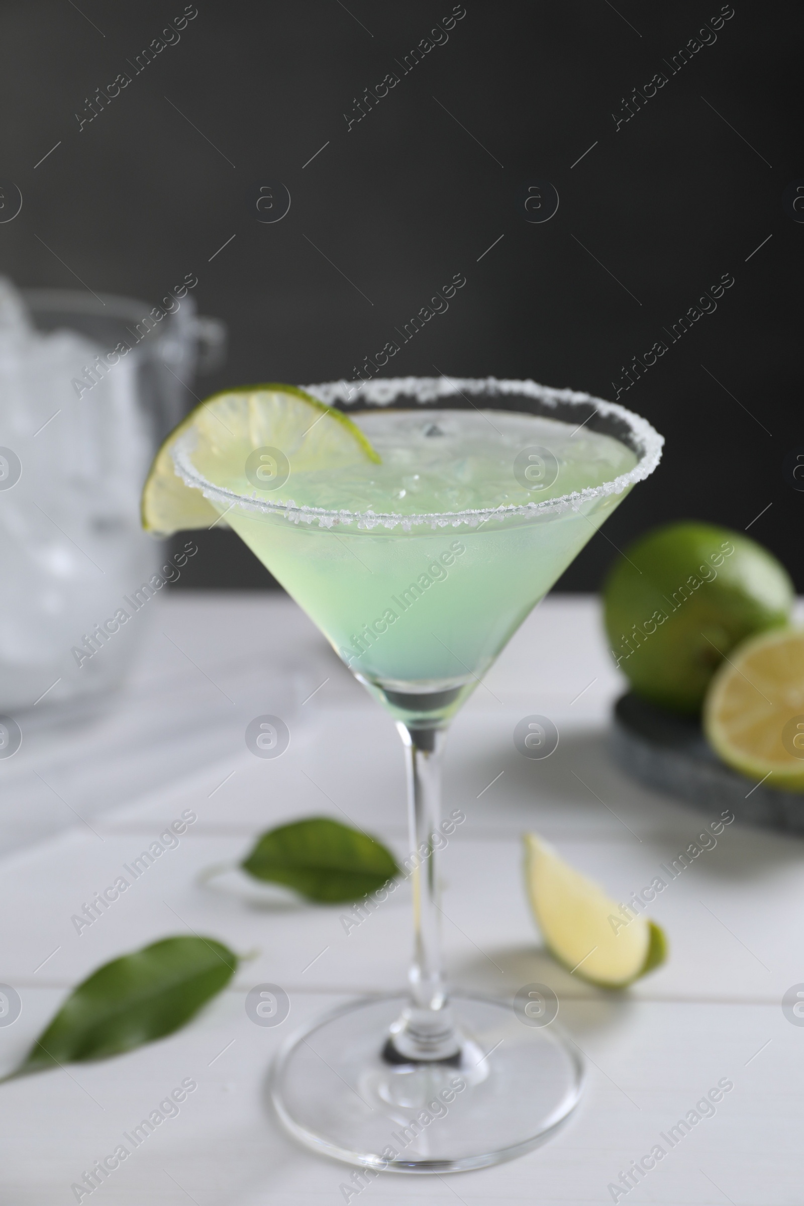 Photo of Delicious Margarita cocktail in glass and lime on white wooden table