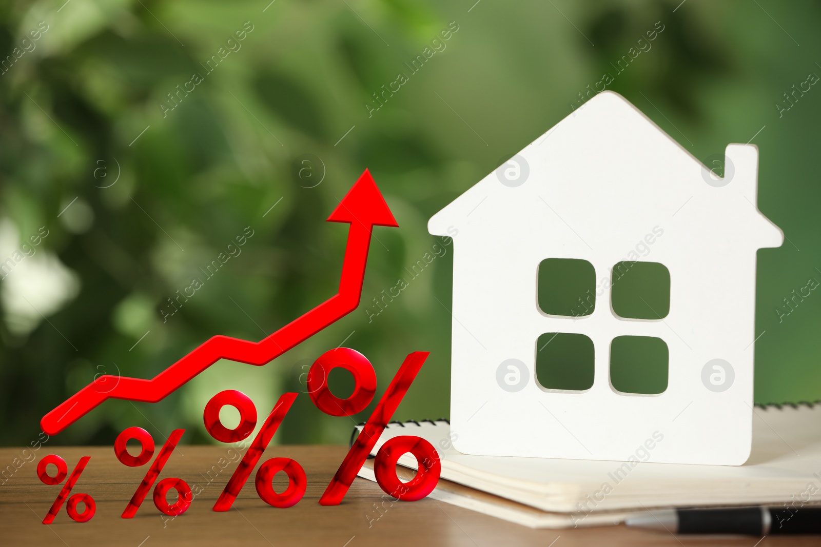 Image of Mortgage rate rising illustrated by percent signs and upward arrow. White house model and notebook on wooden table