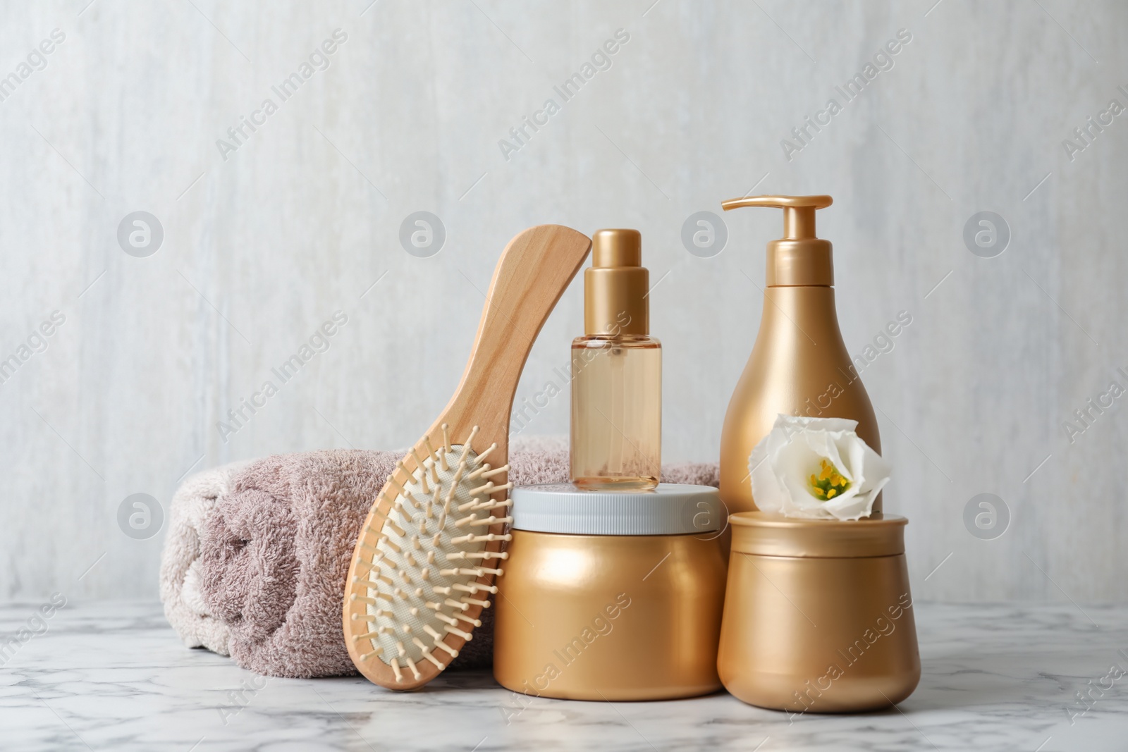 Photo of Different hair products, towel and brush on white marble table