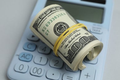 Photo of Money exchange. Dollar banknotes and calculator on gray background, closeup