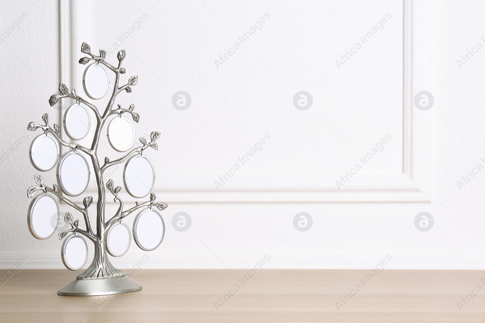 Photo of Blank metal family tree frame on wooden table. Space for text