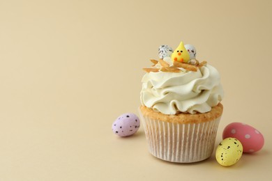 Tasty Easter cupcake with vanilla cream and candies on beige background, space for text