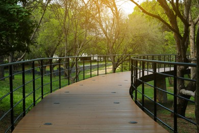 Picturesque view of bridge with metal railing and many trees in park
