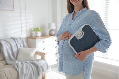 Young pregnant woman with scales at home, closeup