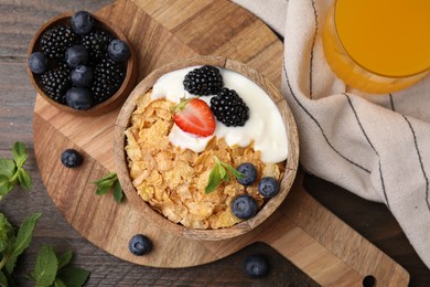 Photo of Delicious crispy cornflakes, yogurt and fresh berries served on wooden table, flat lay. Healthy breakfast