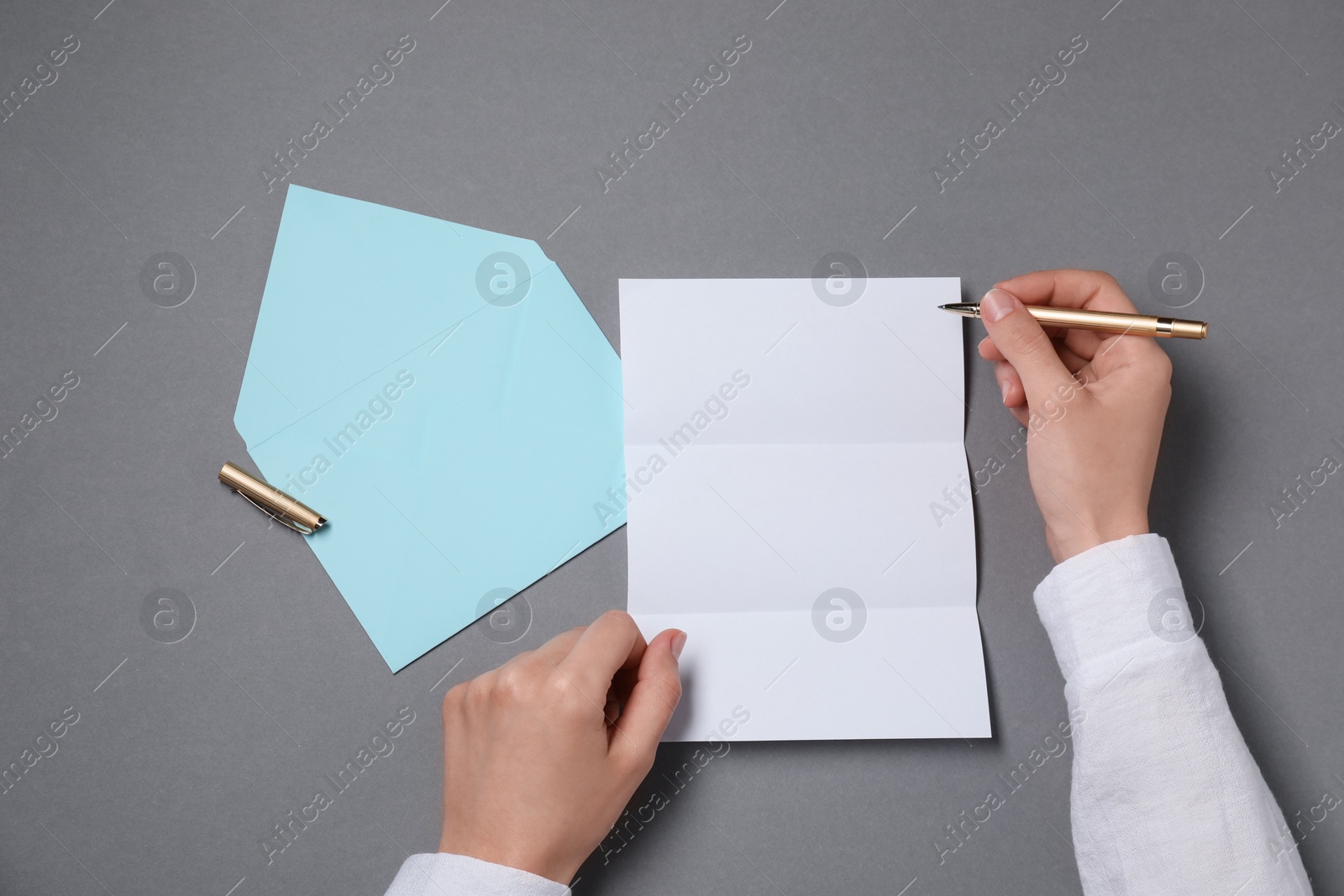 Photo of Woman writing letter at grey table, top view. Space for text
