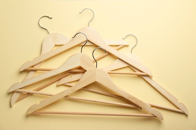 Photo of Wooden hangers on pale yellow background, top view