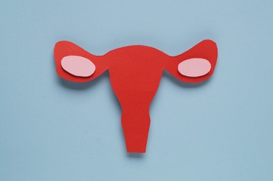 Photo of Woman's health. Paper uterus on light blue background, flat lay