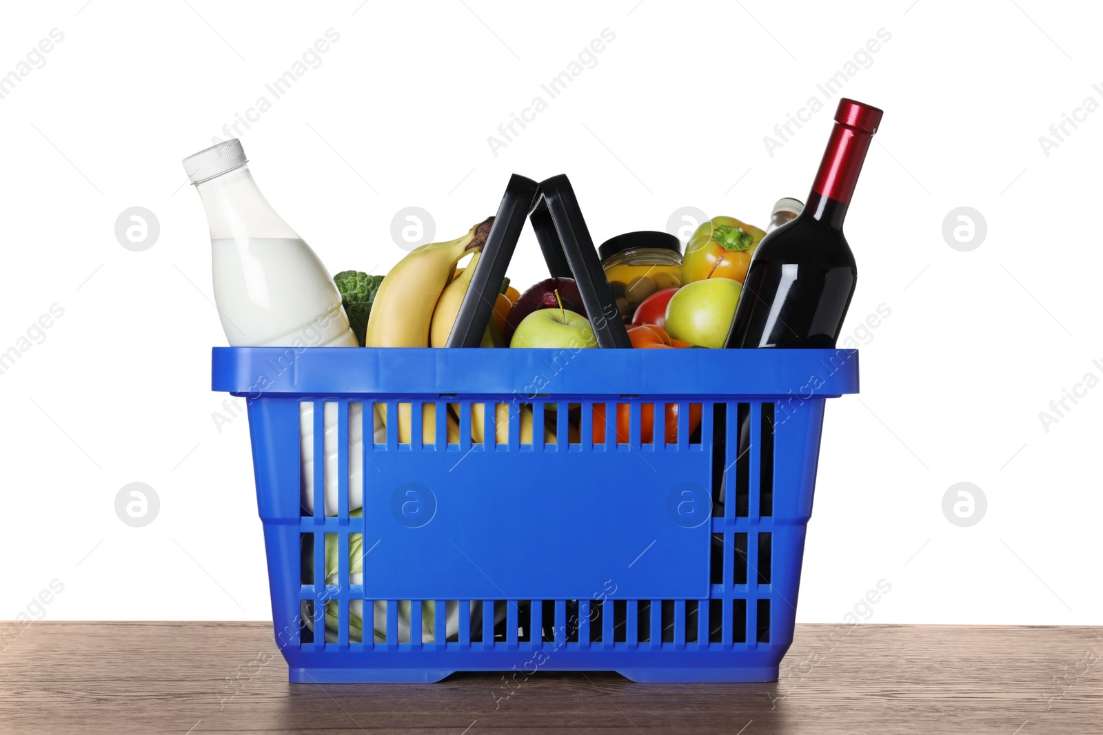 Photo of Shopping basket with grocery products on wooden table against white background