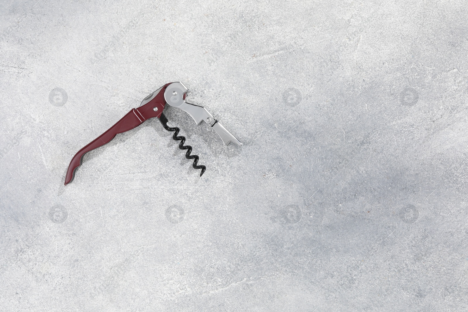 Photo of One corkscrew (sommelier knife) on grey textured table, top view. Space for text