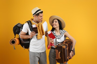 Couple of tourists with tickets, passports and luggage on yellow background