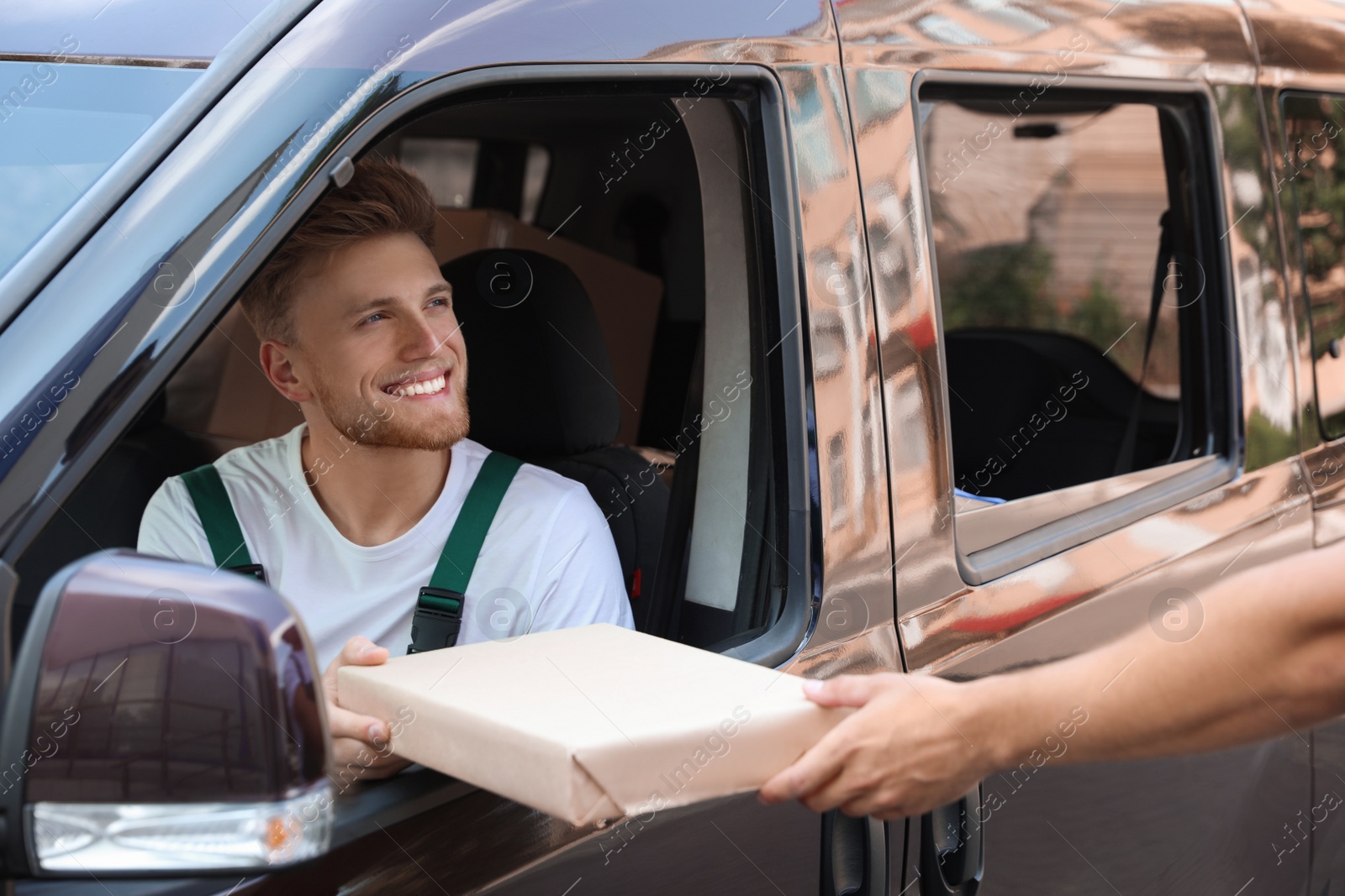 Photo of Young delivery courier giving parcel to customer outdoors
