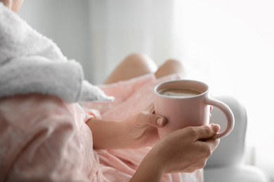 Photo of Woman with cup of hot drink at home in morning, closeup