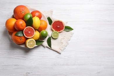 Different citrus fruits on white wooden table, flat lay. Space for text