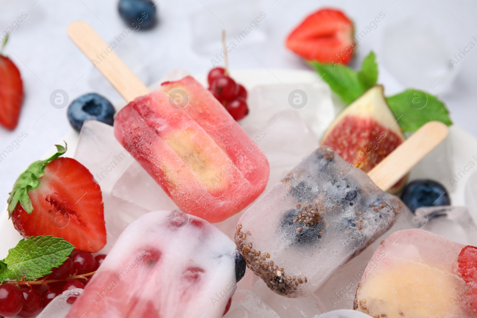 Photo of Tasty refreshing fruit and berry ice pops on table, closeup