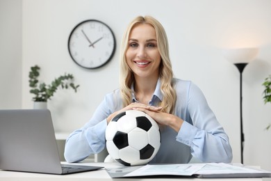 Photo of Happy woman with soccer ball at table in office