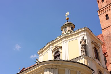 Photo of Facade of old building with sculptures against blue sky, low angle view