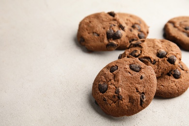 Photo of Tasty chocolate chip cookies on light background. Space for text