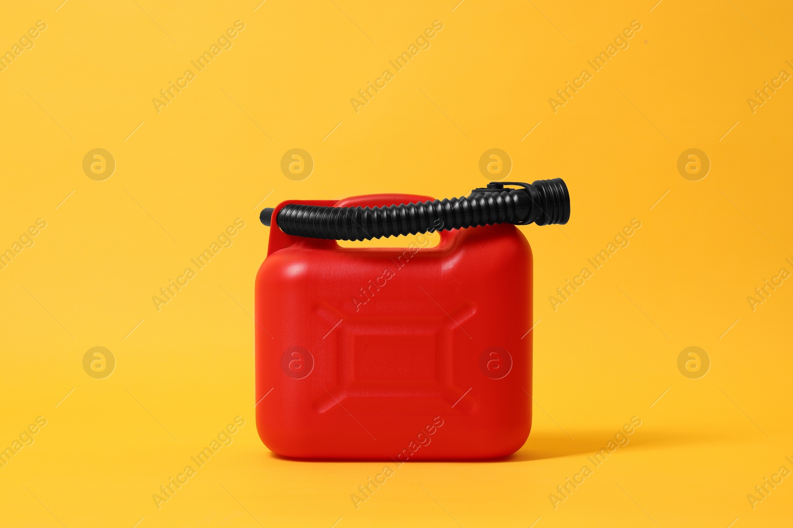 Photo of Red plastic canister with tube on orange background