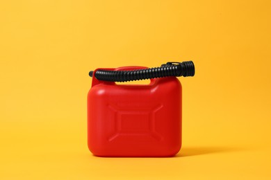 Photo of Red plastic canister with tube on orange background
