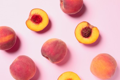 Cut and whole fresh ripe peaches on pink background, flat lay