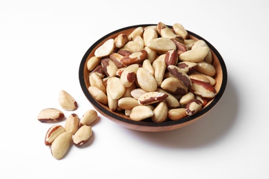 Photo of Wooden bowl with Brazil nuts on white background