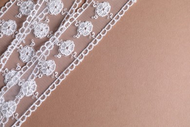 White lace on beige background, top view. Space for text