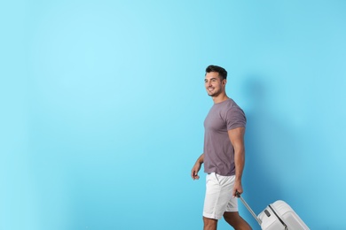 Photo of Young man walking with suitcase on color background