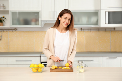 Photo of Young woman making lemon water in kitchen