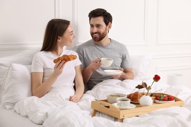 Happy couple having tasty breakfast in bed at home