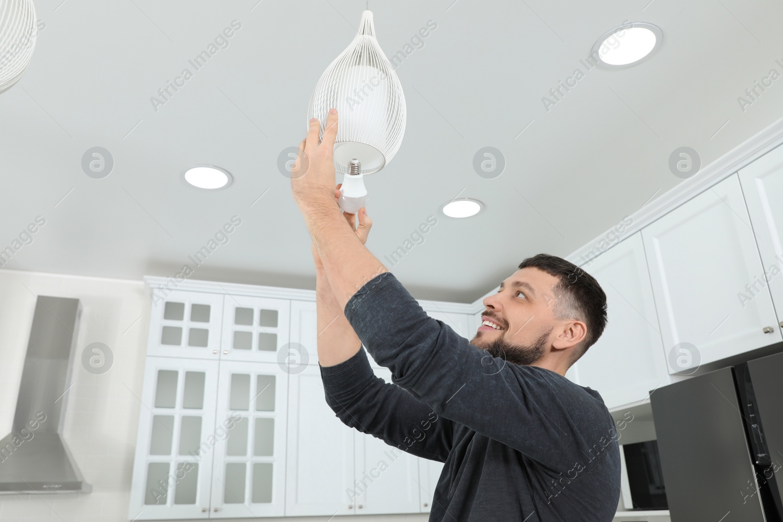 Photo of Man changing light bulb in lamp at home