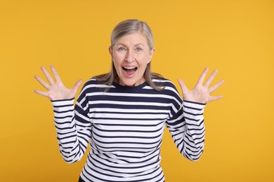 Photo of Portrait of surprised senior woman on yellow background