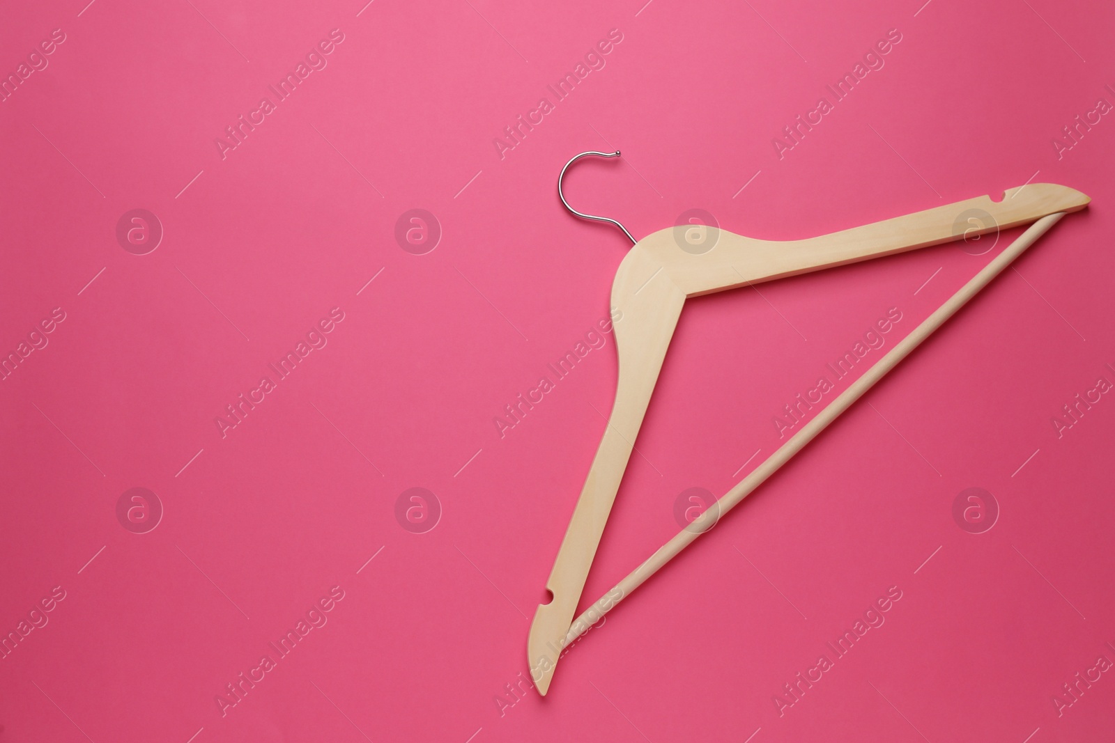 Photo of Empty wooden hanger on pink background, top view. Space for text