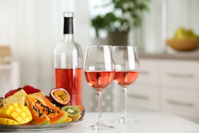 Delicious exotic fruits and wine on white table indoors