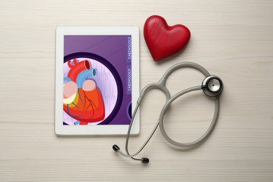 Photo of Flat lay composition with tablet and red heart on white wooden table. Cardiology concept