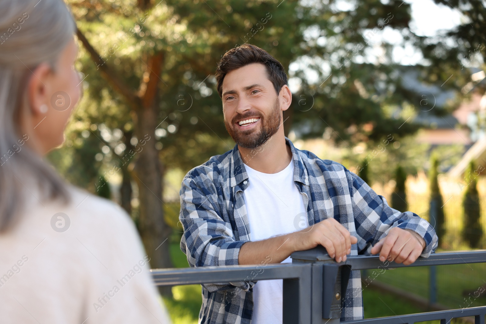 Photo of Friendly relationship with neighbours. Happy man and senior woman near fence outdoors