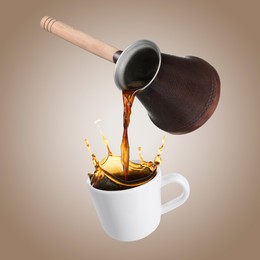 Pouring freshly brewed aromatic coffee from turkish pot into cup. Objects in air on dark beige background