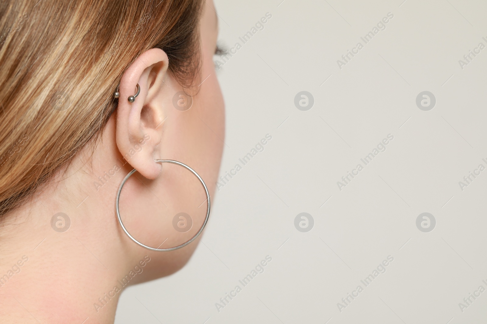 Photo of Young woman with ear piercing on white background, closeup. Space for text