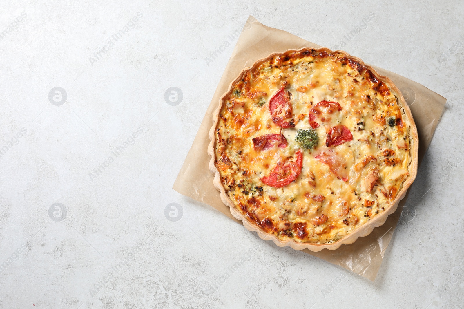 Photo of Tasty quiche with cheese and tomatoes on light grey table, top view. Space for text