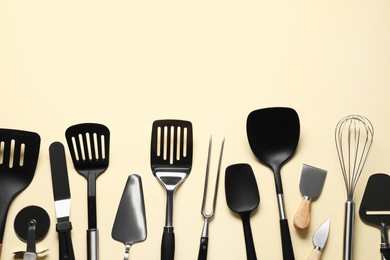 Photo of Different spatulas and other kitchen utensils on beige background, flat lay. Space for text