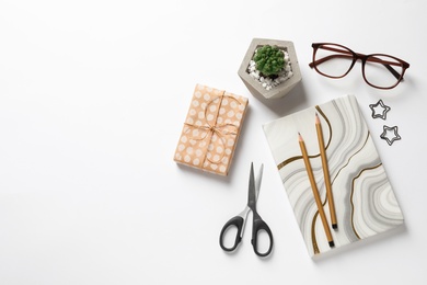 Composition of scissors, notebook and cactus on white background, top view