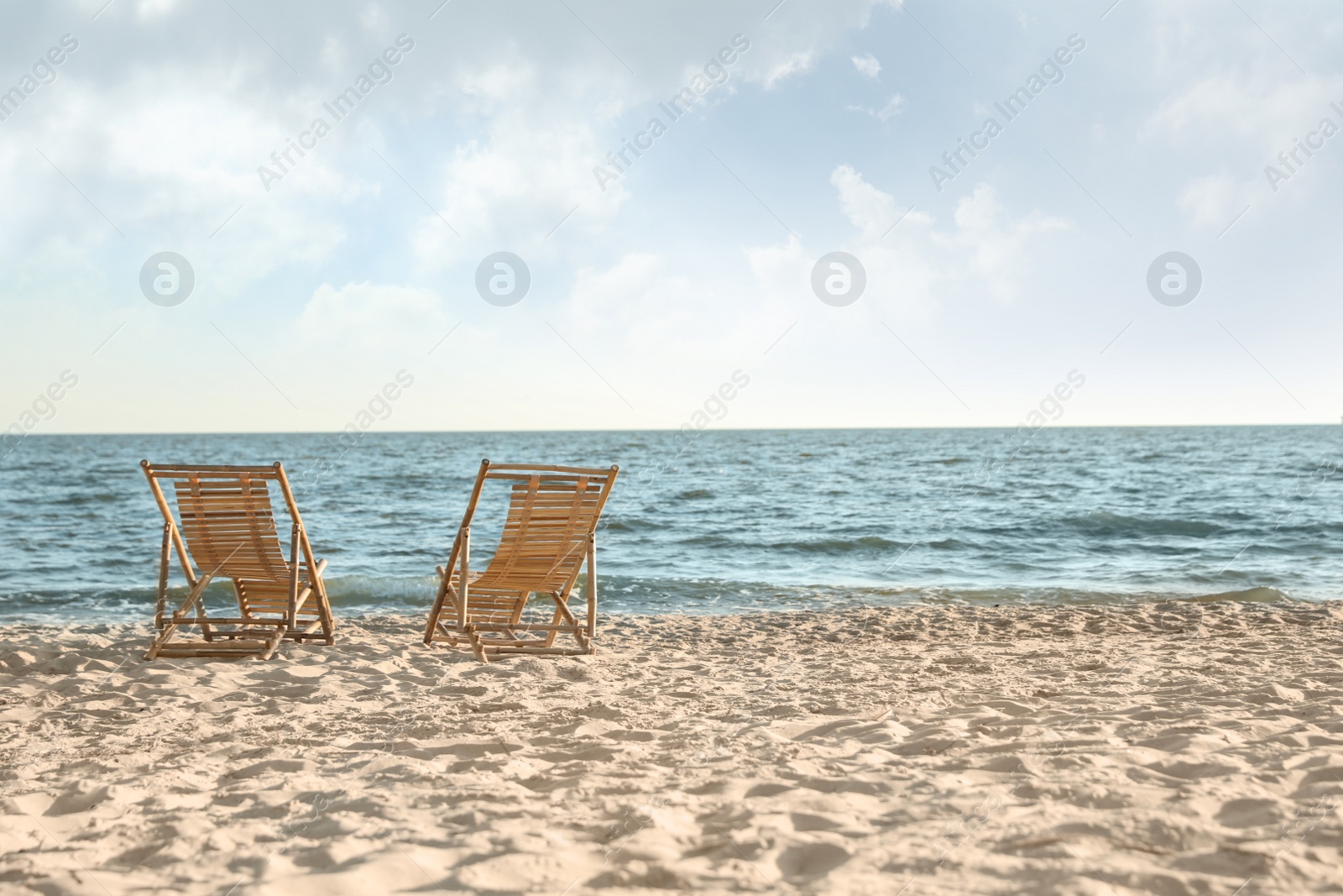 Photo of Wooden deck chairs on sandy beach near sea