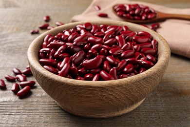 Raw red kidney beans in bowl on wooden table, closeup