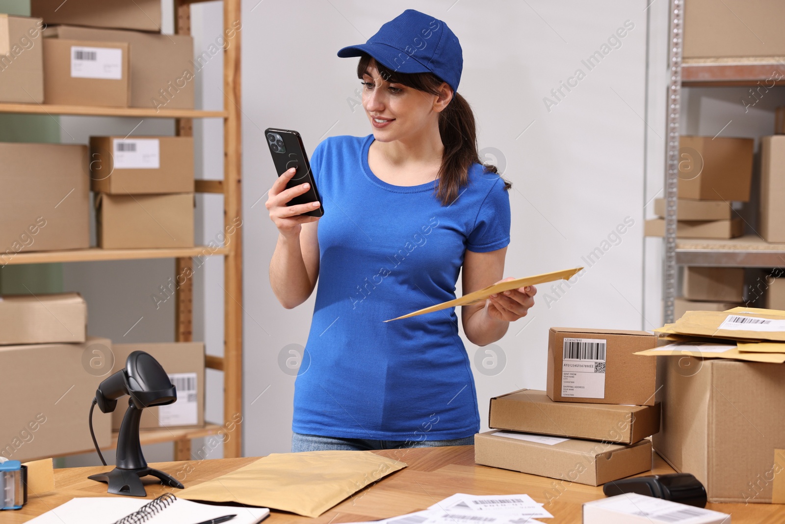 Photo of Parcel packing. Post office worker with smartphone and bag indoors