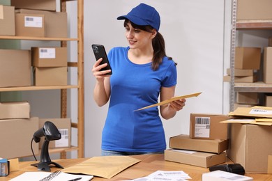 Parcel packing. Post office worker with smartphone and bag indoors