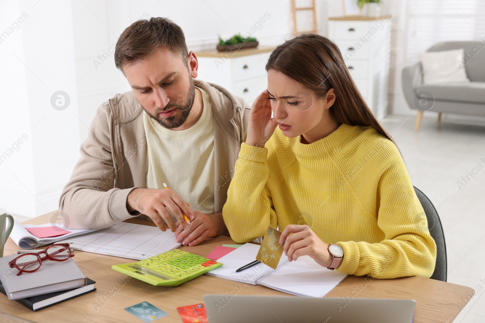 Photo of Young couple discussing family budget at table in living room